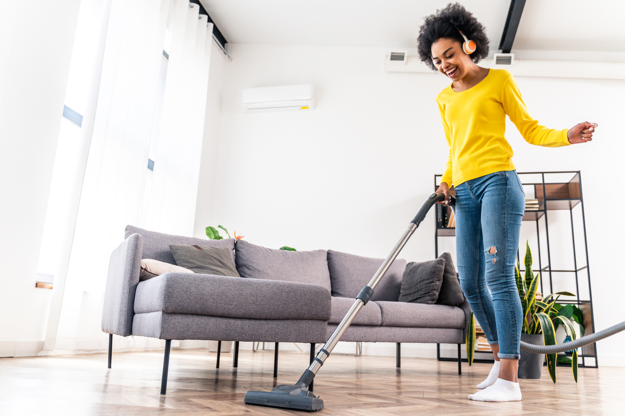 Happy woman cleaning home with vacuum cleaner and listening music - Housewife doing her homeworks, domestic life scene